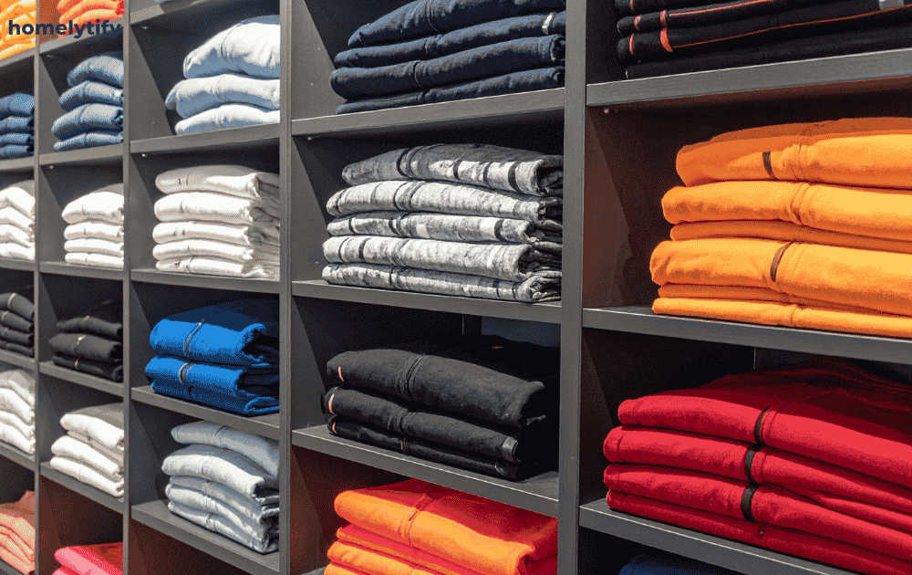 Folding and storing clothes neatly on shelves — an easy small bedroom organization idea on a budget.