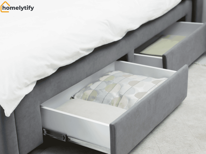 Pull-out storage drawers built into a grey upholstered bed frame, a practical bedroom DIY under-bed and closet solution for organizing bedding and linens