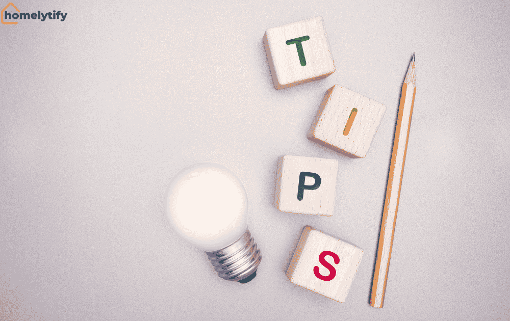Wooden blocks spelling TIPS with a glowing light bulb and pencil representing budget home tips.