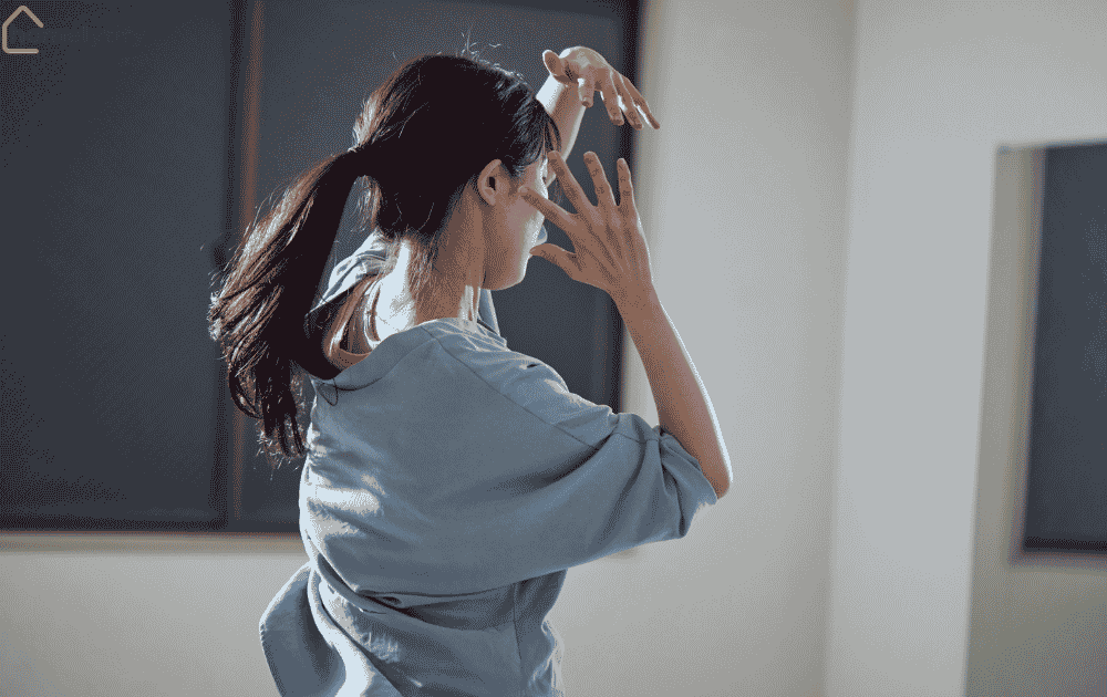 Light movement morning routine — woman stretching arms indoors in soft natural light.