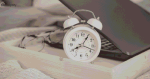 Morning routine ideas with an alarm clock showing 8:40, glasses, and a laptop on a wooden tray in a cozy bedroom setting.