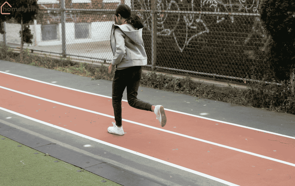 A person jogging on a red running track in a hoodie and sneakers, my personal experience starting a morning routine with exercise.
