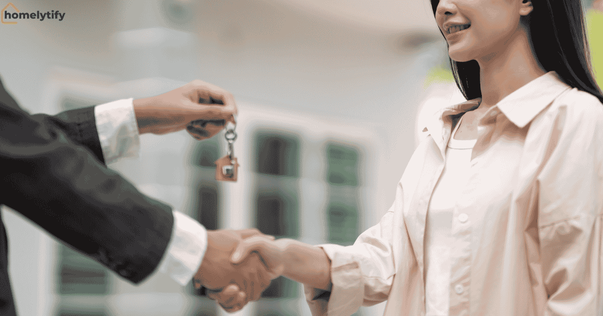 A landlord handing house keys to a smiling tenant with a handshake — a fresh start to organize a rental home