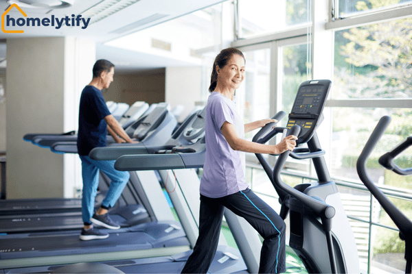 Physical activation in morning routine — woman exercising on an elliptical machine in a bright gym.