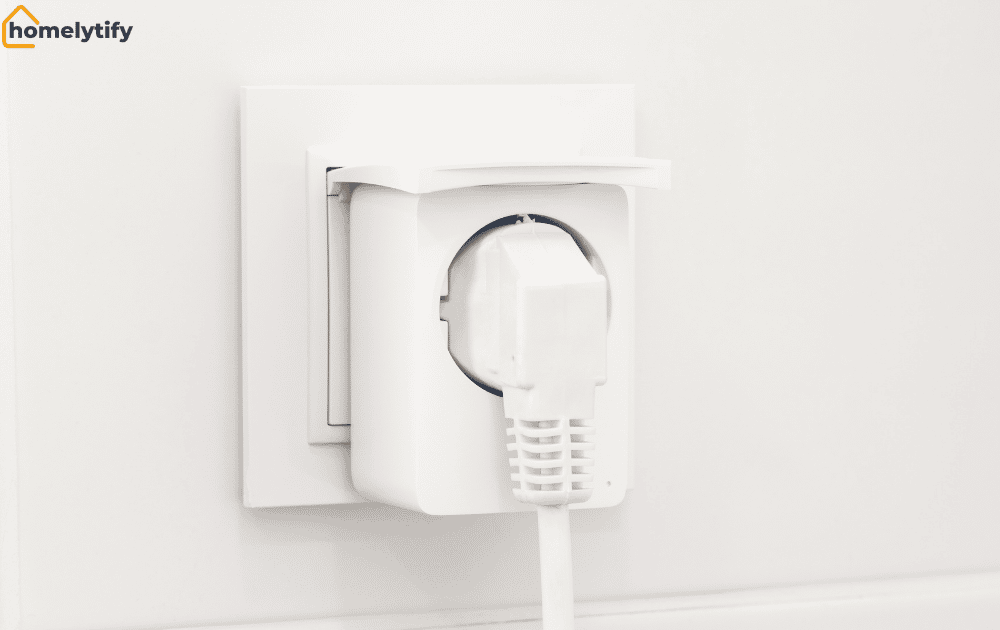 A white smart plug is inserted into a wall outlet with a power cable connected in a home setting