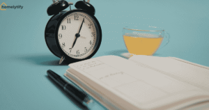 Alarm clock, journal, pen, and herbal tea on blue background for building a morning routine from scratch.