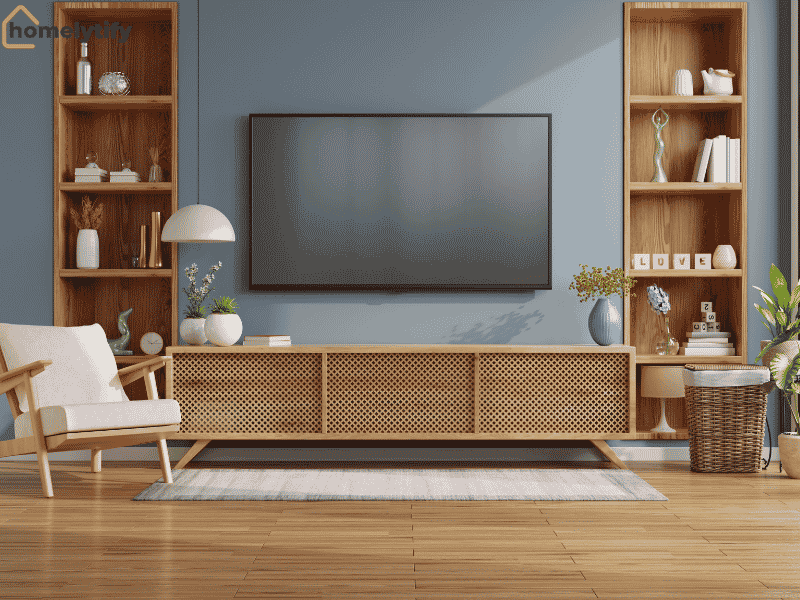 Living room with wooden wall-mounted shelves on either side of a TV, styled with books, vases, and decor above a rattan media console