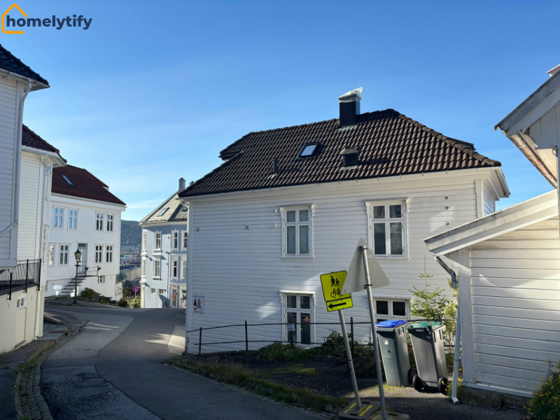 Quiet residential street with white housing properties representing monthly rent and mortgage costs