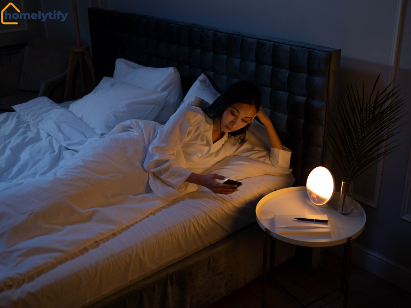 A woman lying in bed at night to prep for tomorrow, with a warm bedside lamp and notepad nearby