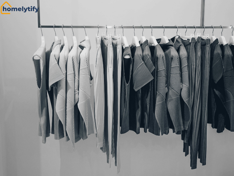 Clothes sorted by category on a single rod, grouped from light to dark striped tops and jackets in a minimal closet 