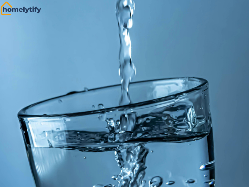 Fresh water pouring into a clear glass on a blue background