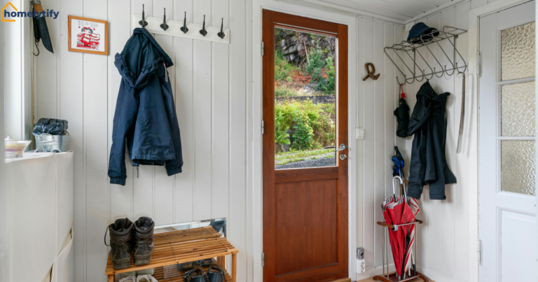 Small entryway organization with wall hooks for coats, wooden shoe rack, and umbrella stand maximizing narrow hallway storage