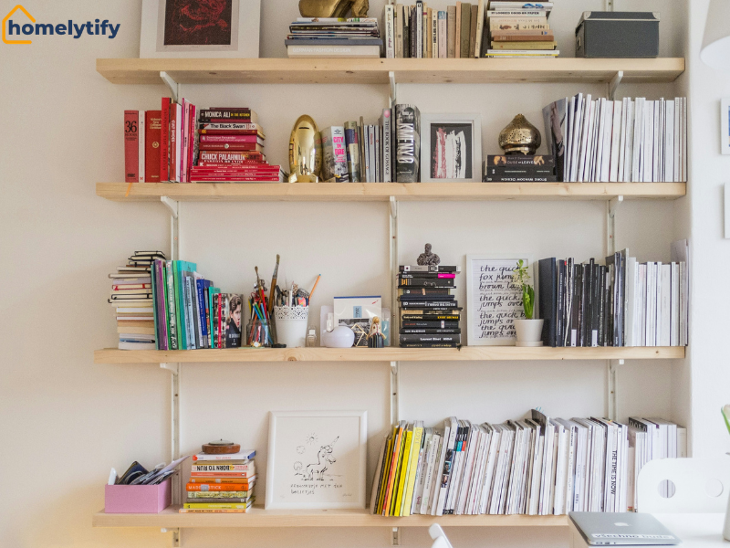 Floating shelves filled with colorful books, decor, and magazines, a stylish wall storage solution for a small living room.
