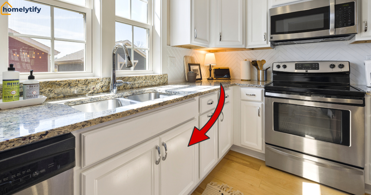 White kitchen cabinet with a red arrow pointing down to the sink base, showing how to organize under the kitchen sink