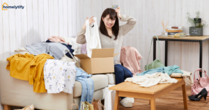 Woman surrounded by clothing clutter and shopping bags on couch, illustrating how to stop clutter from coming back at home