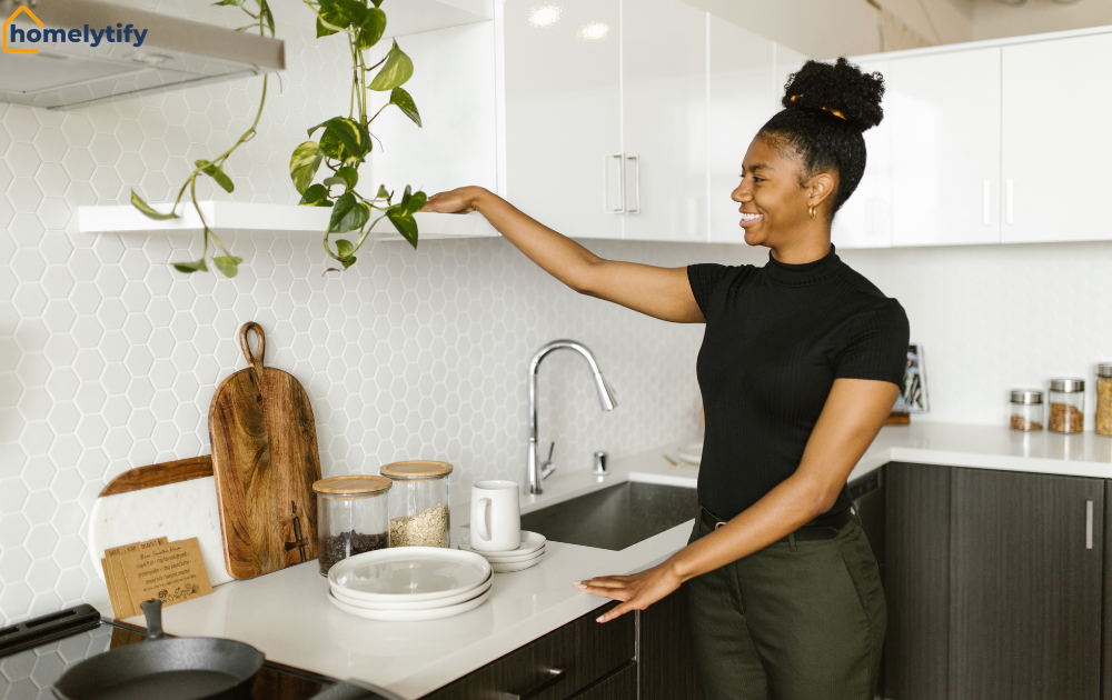 Woman reaching to organize kitchen cabinets above a white countertop with jars and cutting boards