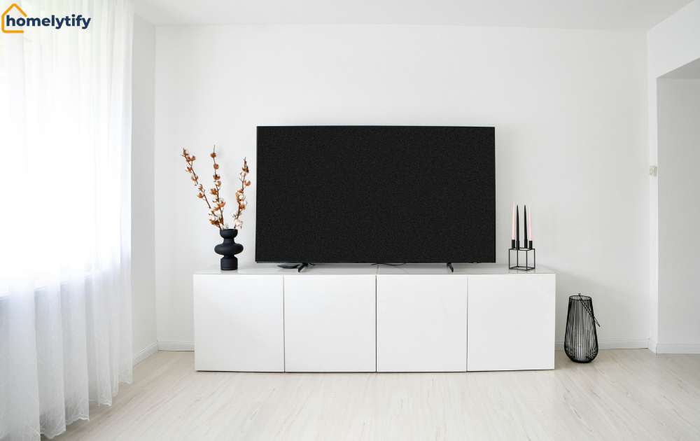Organizing cables behind an entertainment center with a clean white TV console