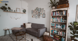 Small apartment living room storage idea with a tall white bookshelf, gray sectional sofa, gallery wall, and cozy boho decor in a compact space